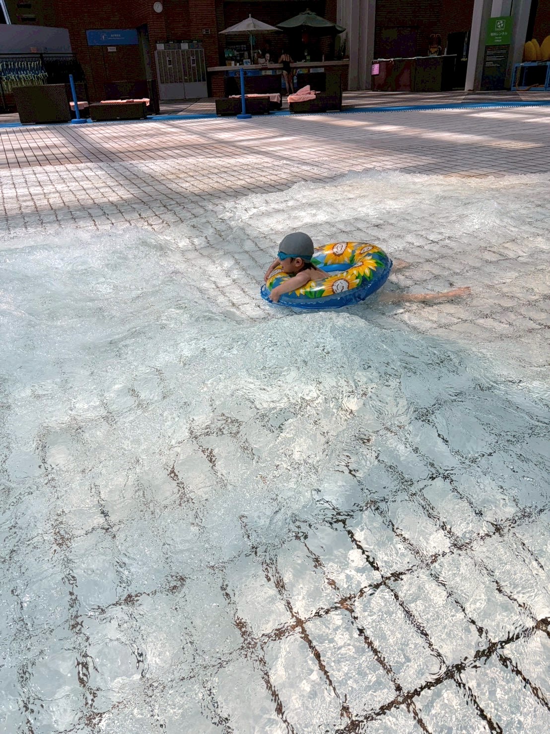 ウェーブプールで浮き輪に乗る子ども